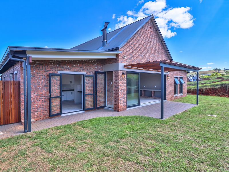 Rear view of a modern brick house featuring a covered patio with a timber pergola, sliding glass doors, and a well-maintained garden.