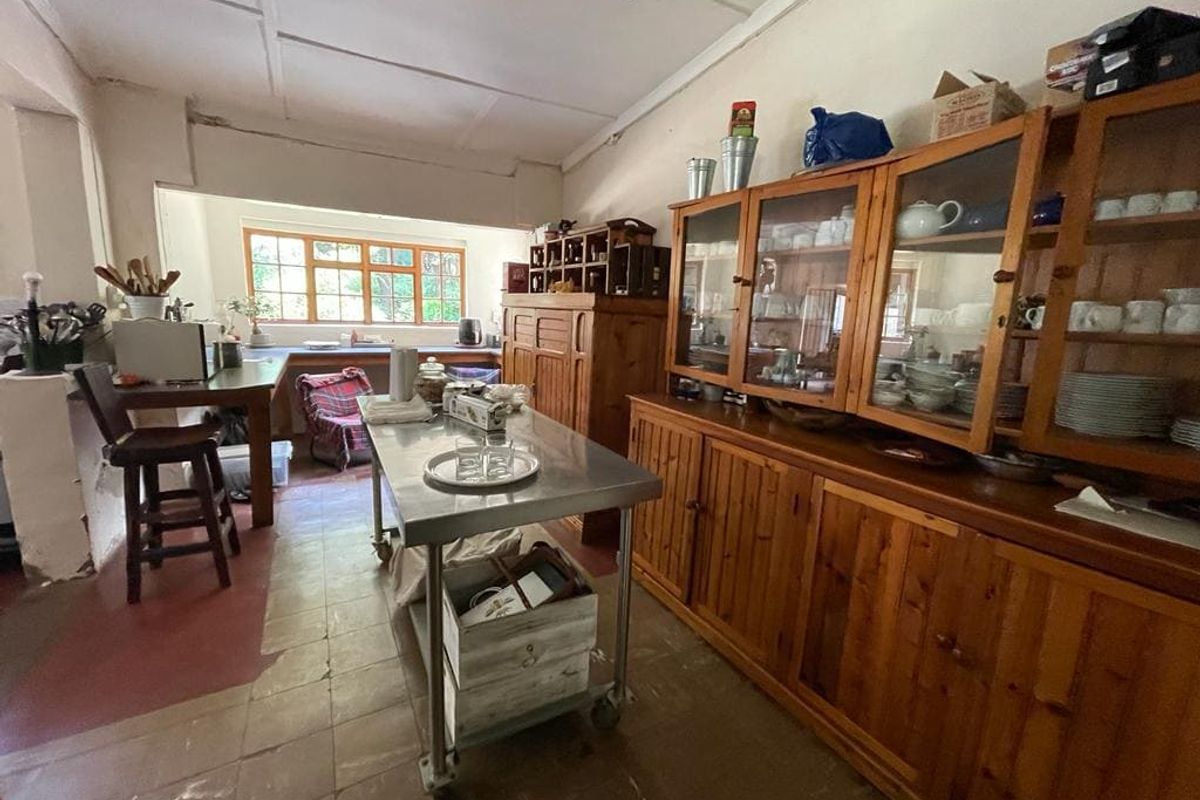 A dated kitchen area featuring wooden cabinetry, tiled flooring, and a central stainless steel prep table, offering potential for modernization and renovation.