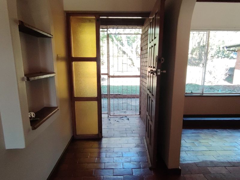 Entrance hall featuring terracotta tile flooring, a built-in wall niche, and direct access to the exterior through a security gate and timber door.