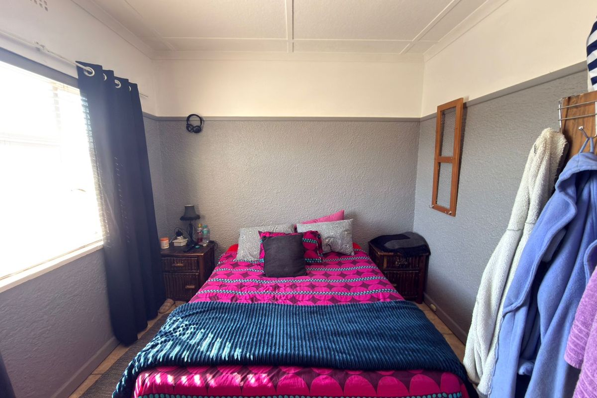 A bedroom featuring textured walls with a picture rail and coved ceiling, providing a functional space with natural light.