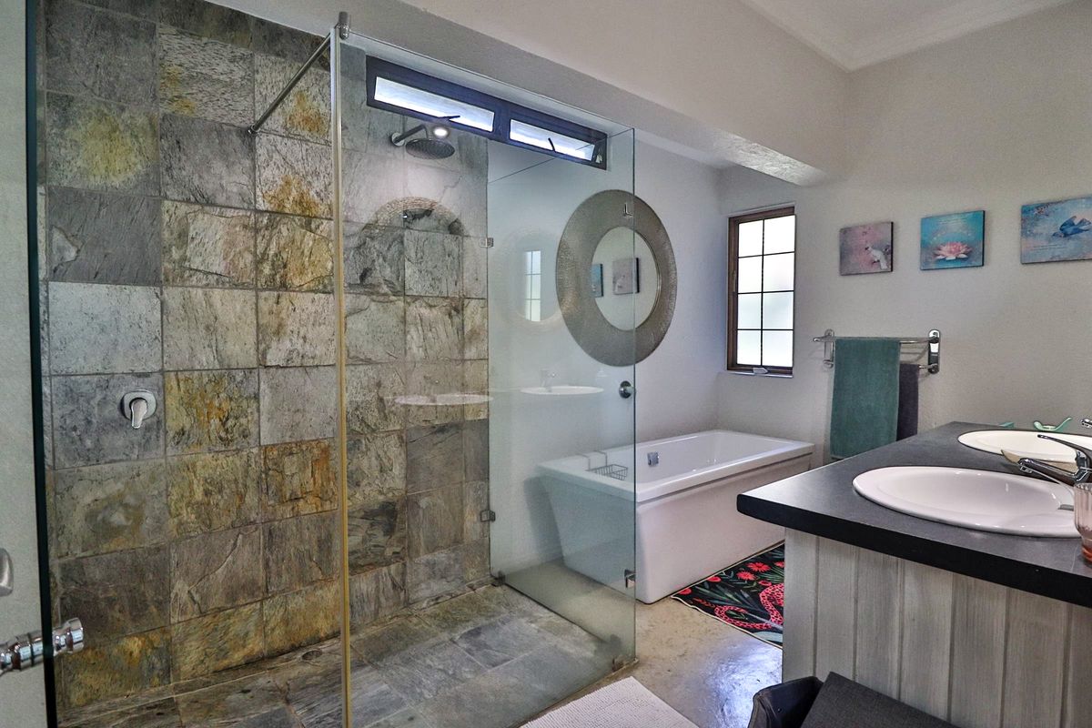 Modern bathroom featuring a spacious walk-in shower with stone tiling, a freestanding bathtub, and a double vanity with ample counter space.