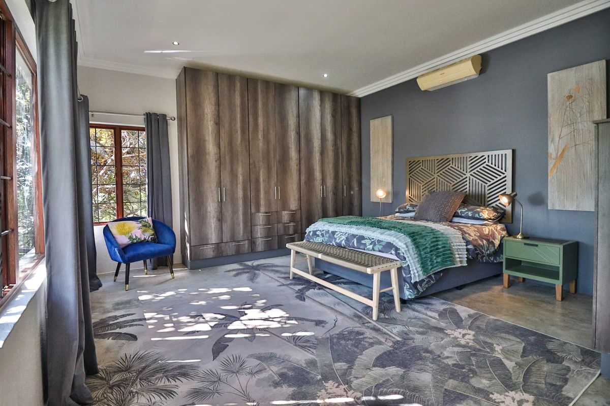 Spacious bedroom featuring extensive built-in cabinetry, a wall-mounted air conditioning unit, and large windows allowing for natural light.