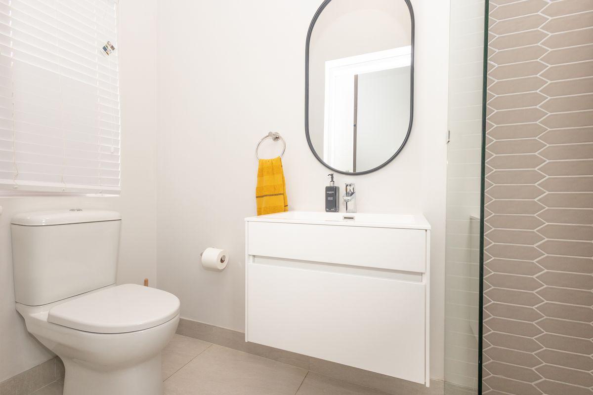 Modern bathroom featuring a wall-mounted vanity, ceramic toilet, and a tiled shower enclosure with a glass screen.