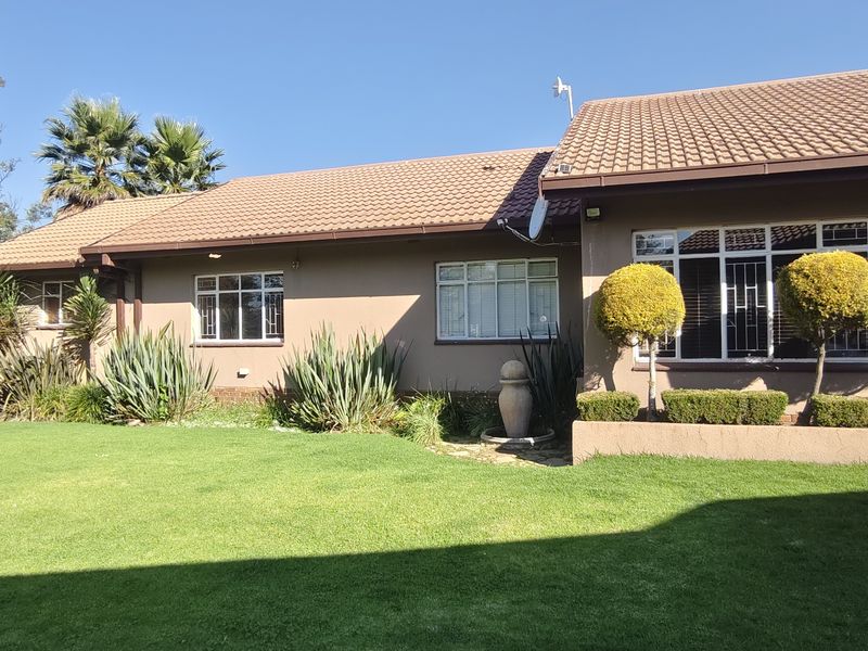 A well-maintained rear exterior view of the house featuring a tiled roof, landscaped garden, and secure aluminium-framed windows.