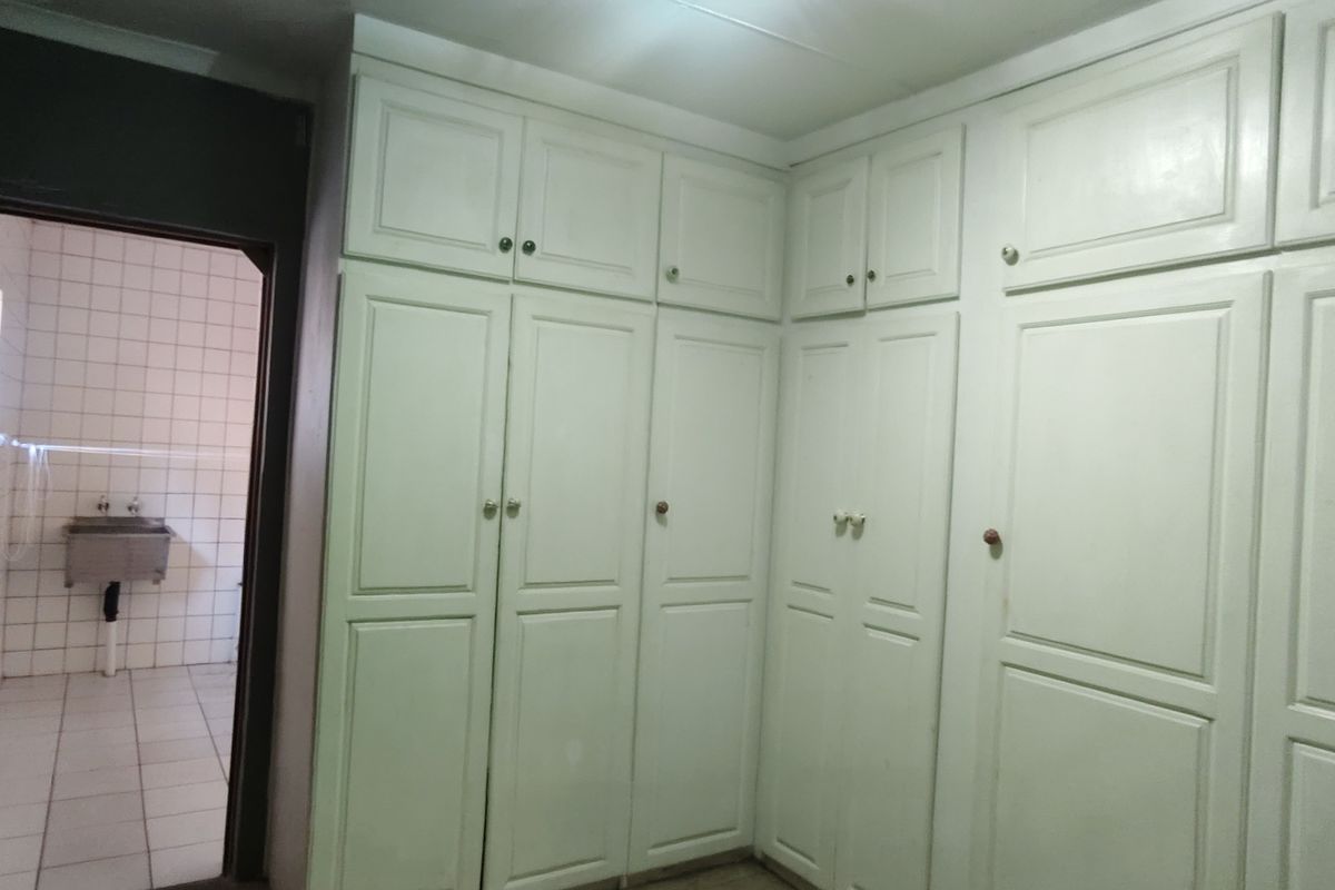 A bedroom featuring extensive built-in cabinetry and direct access to an adjacent tiled utility or wash area.