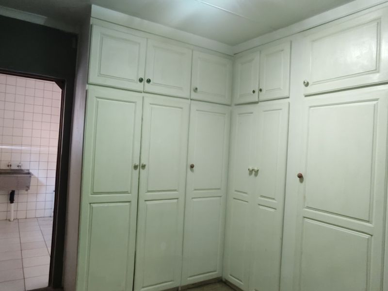 A bedroom featuring extensive built-in cabinetry and direct access to an adjacent tiled utility or wash area.