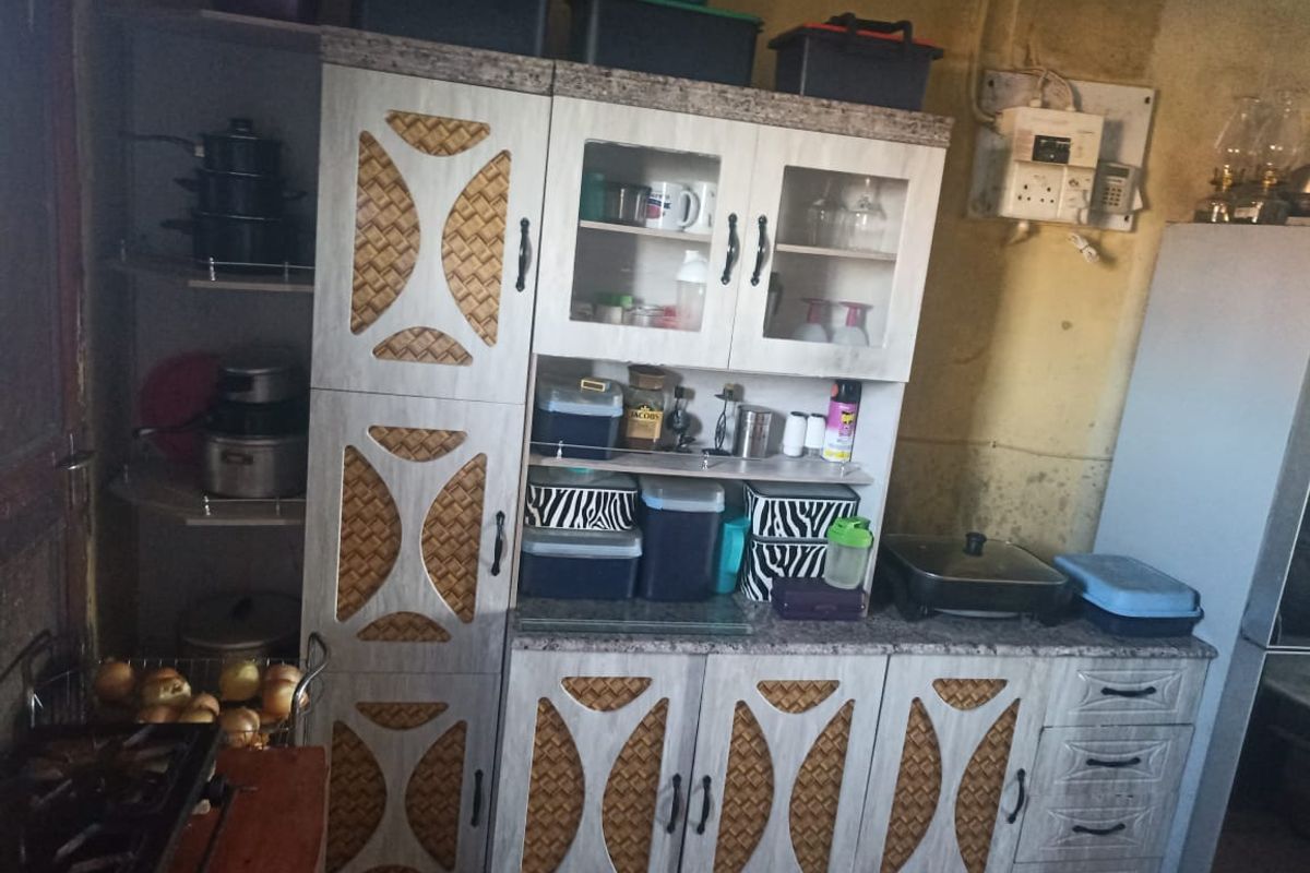 A kitchen area featuring built-in cabinetry with patterned doors and laminate countertops, requiring cosmetic updates to the wall finishes.