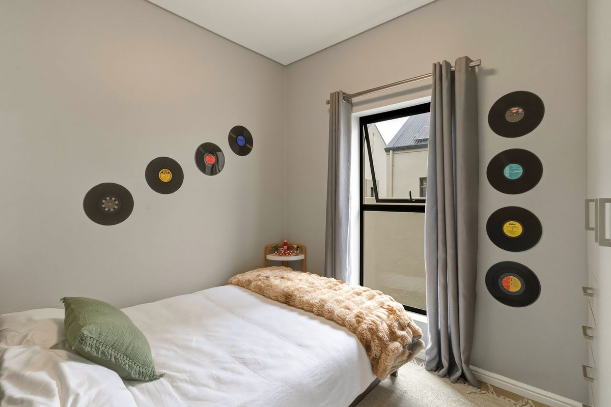 A well-maintained bedroom featuring neutral wall tones, a modern window with curtain rod, and built-in cabinetry.