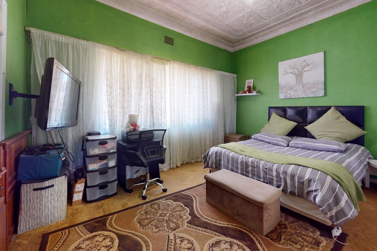 A bedroom featuring a traditional pressed metal ceiling, cornice detailing, and cork flooring, offering a classic foundation for a modern interior update.