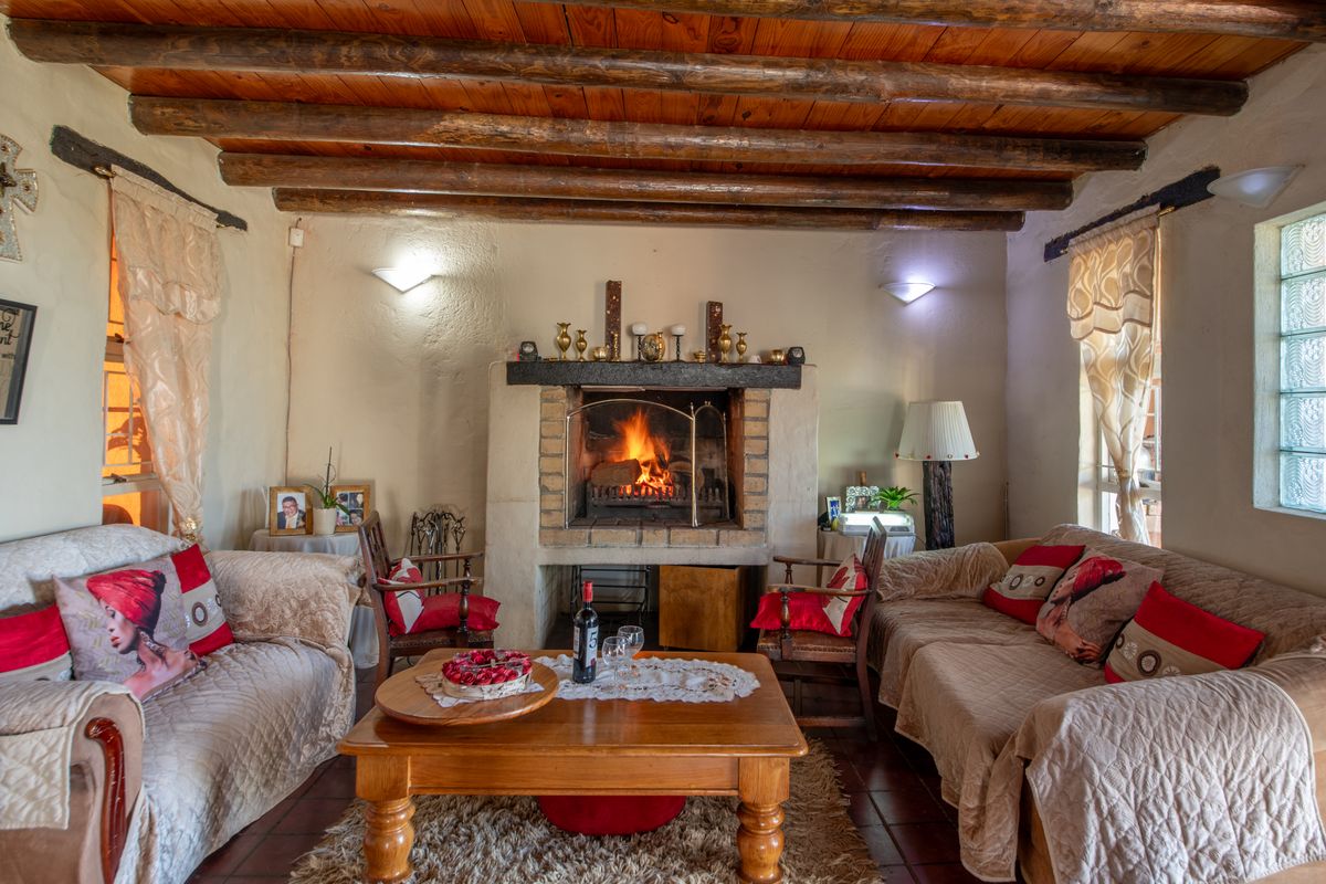 Cozy living room featuring a rustic exposed timber beam ceiling and a traditional built-in brick fireplace as a central focal point.