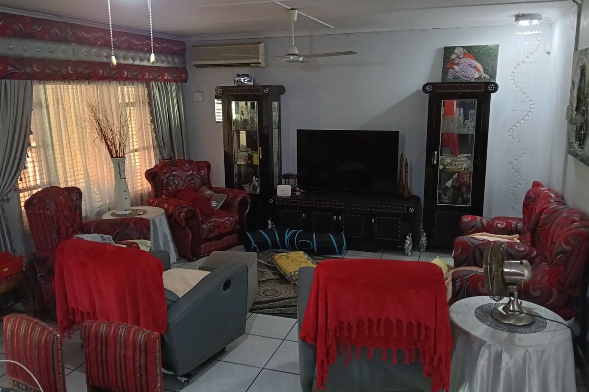 A spacious living room featuring tiled flooring, a ceiling fan, and a wall-mounted split system air conditioner.