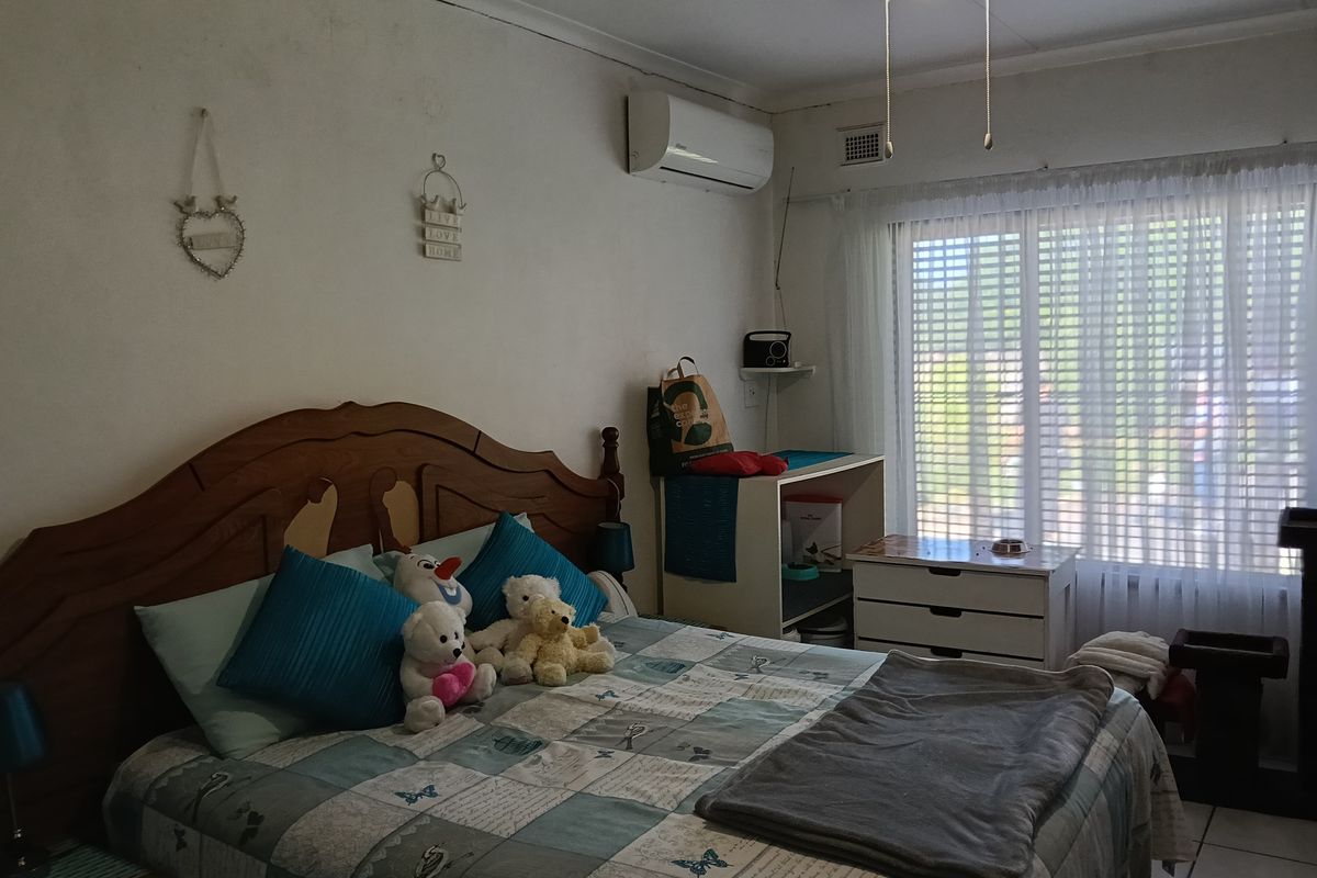 A functional bedroom featuring a split-system air conditioner, ceiling fan, and tiled flooring, offering a comfortable and practical living space.