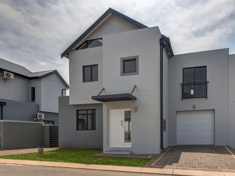 Modern two-story residential home featuring a grey facade, integrated garage, paved driveway, and a small front lawn.