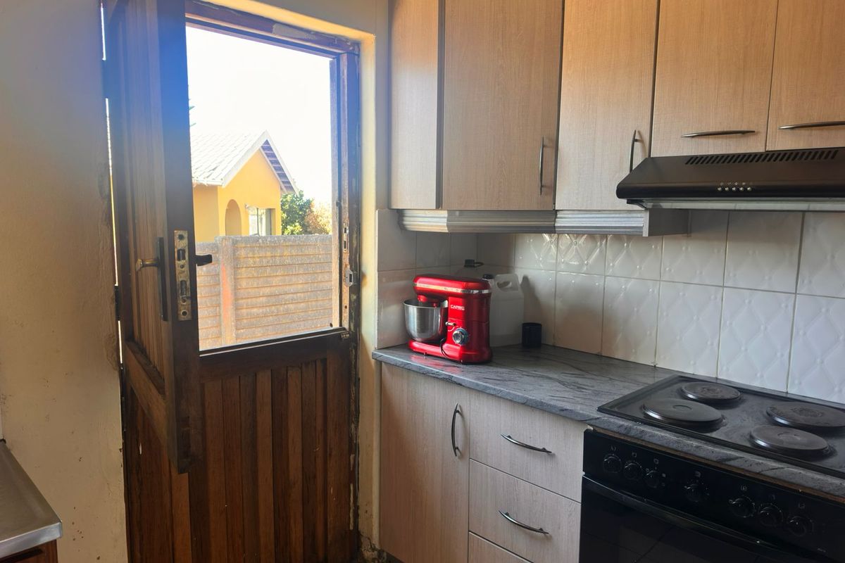 A functional kitchen area featuring built-in cabinetry, a stove with extractor fan, and a stable door leading to the exterior.