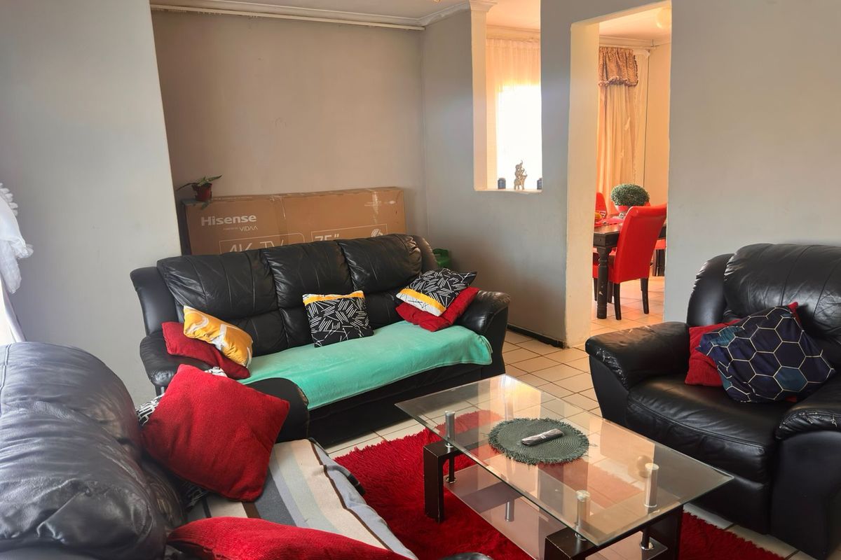 A living room featuring tiled flooring and an open archway leading to the dining area, providing a functional and connected living space.
