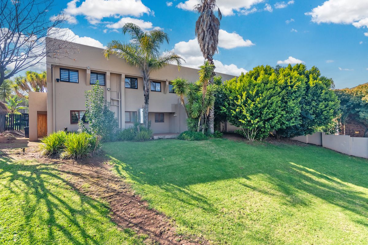Rear view of the apartment building featuring a private lawn, established garden, and exterior security features on the windows.