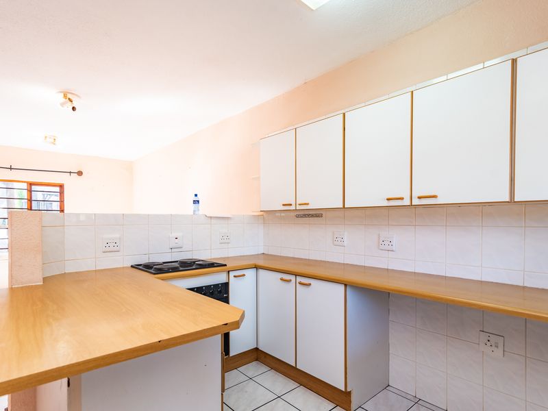 A functional kitchen featuring white cabinetry, laminate countertops, tiled backsplash, and built-in cooking appliances, offering a clean and practical workspace.