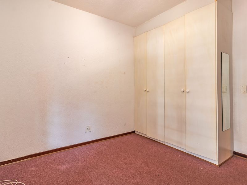 An empty bedroom featuring built-in cupboards and carpeted flooring, offering a blank canvas for renovation or modernization.