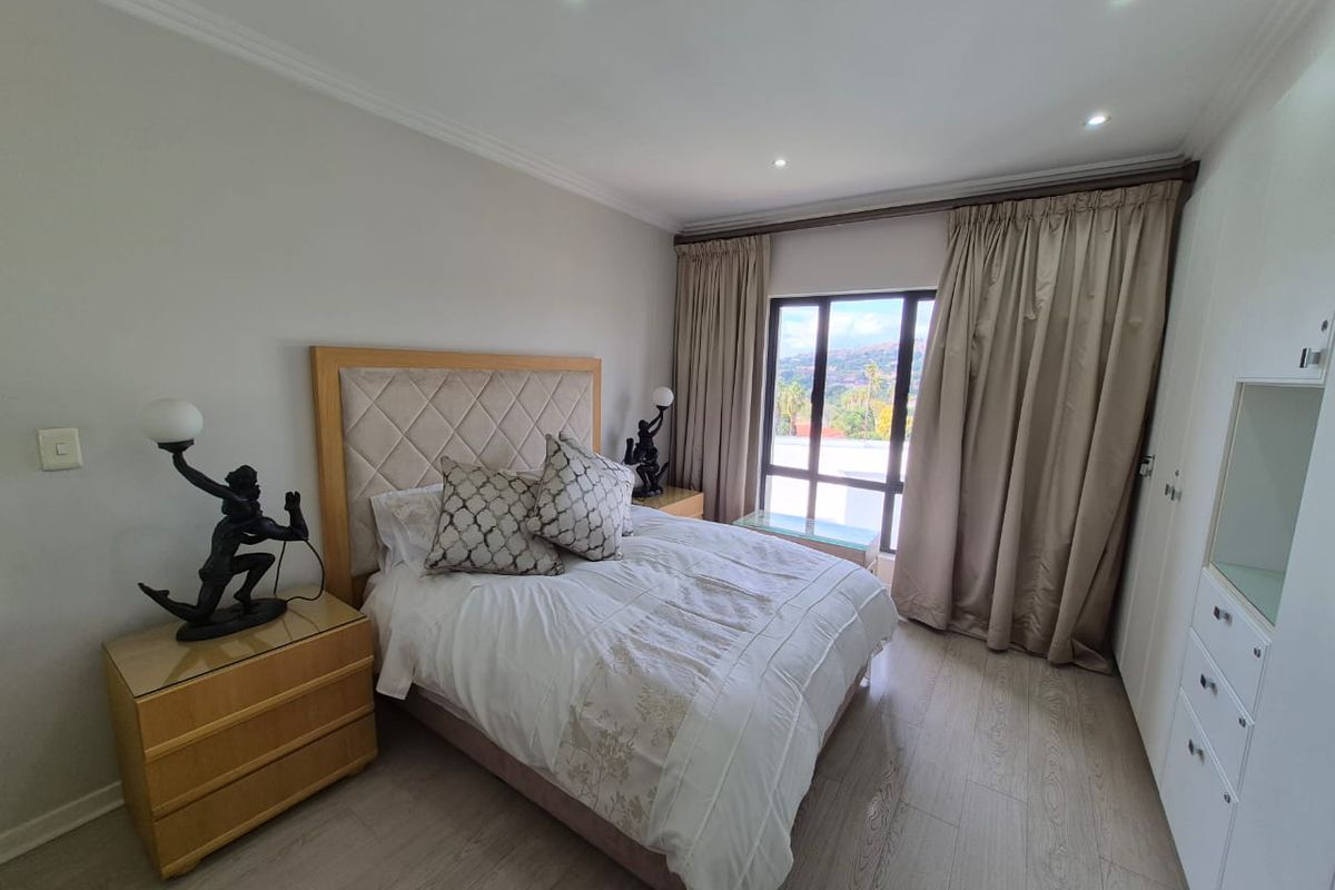 A well-maintained bedroom featuring laminate flooring, recessed downlighting, and built-in cupboards, offering a clean and functional living space.