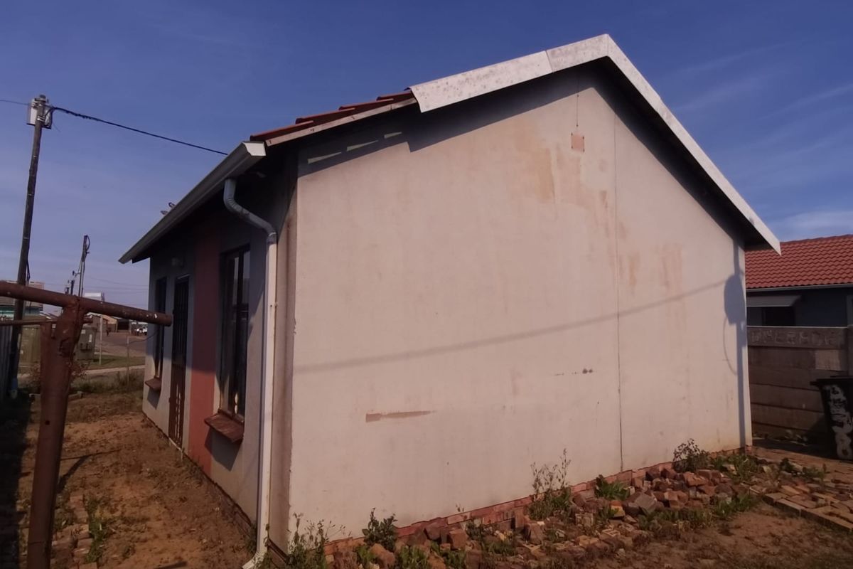 Rear view of the property showing the exterior wall, roofline, and guttering system with surrounding unlandscaped ground.