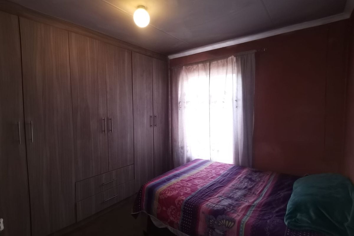 A bedroom featuring extensive built-in wooden cupboards providing ample storage space and a window allowing natural light.