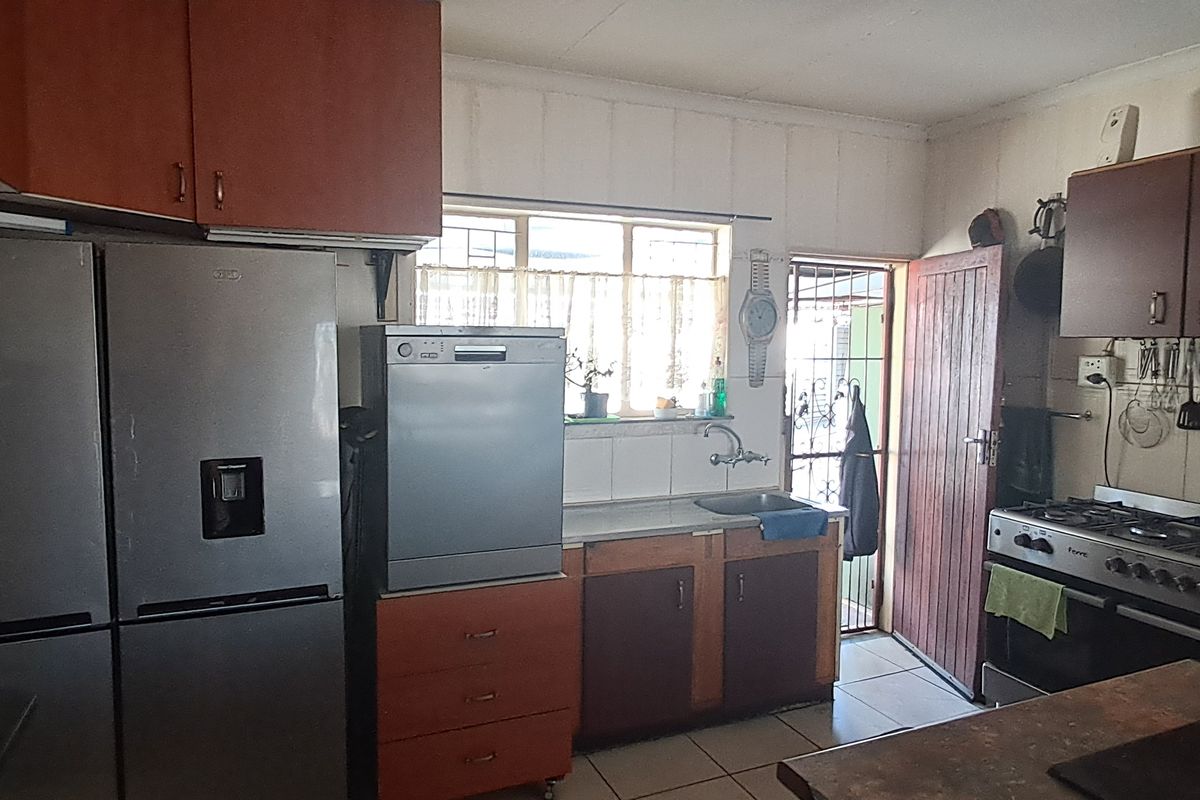 A functional kitchen featuring built-in wooden cabinetry, a gas stove with oven, and tiled flooring with direct access to the exterior.