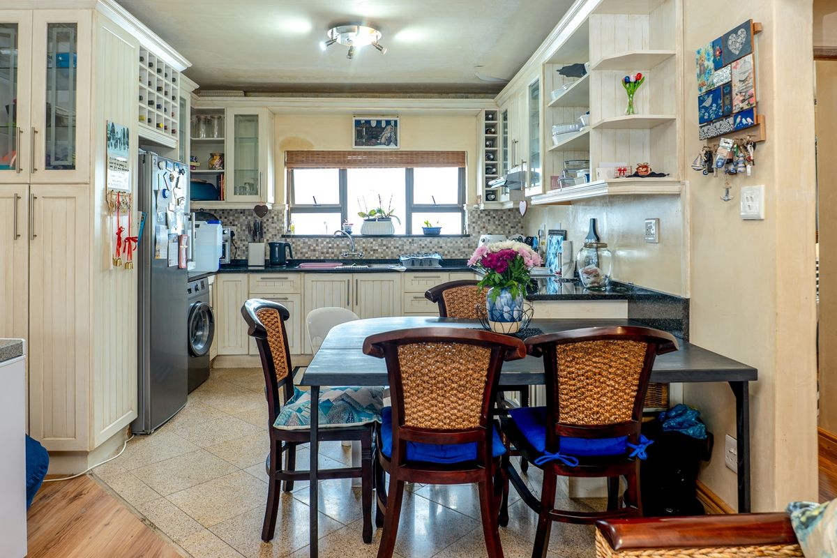 A functional kitchen featuring cream-colored built-in cabinetry, granite countertops, a tiled backsplash, and integrated storage solutions, including a dedicated wine rack.