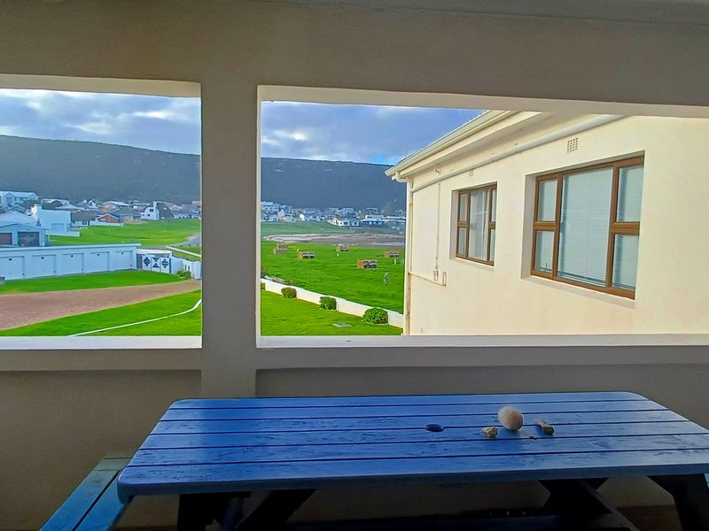 A covered balcony area featuring large window openings that provide expansive views of the surrounding neighborhood and landscape.