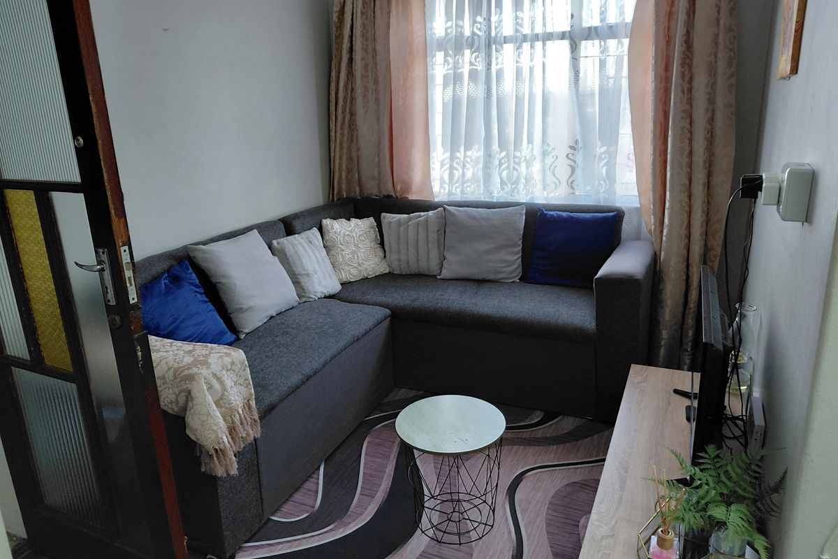 A compact living room area featuring a window with curtains and a standard interior door.