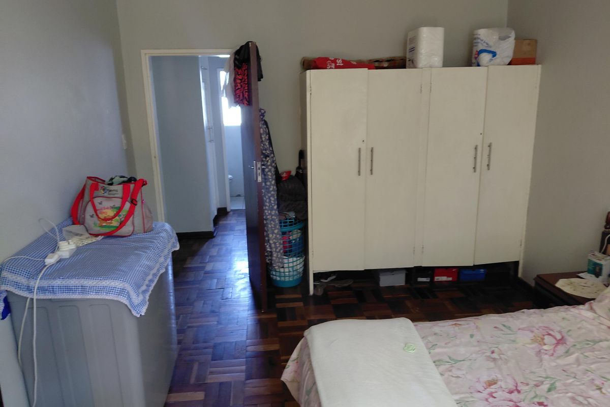 A bedroom featuring classic parquet flooring and a built-in wardrobe, with direct access to an adjoining bathroom.