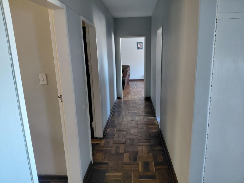 A functional hallway featuring classic parquet flooring and built-in storage cupboards, providing access to multiple rooms within the townhouse.