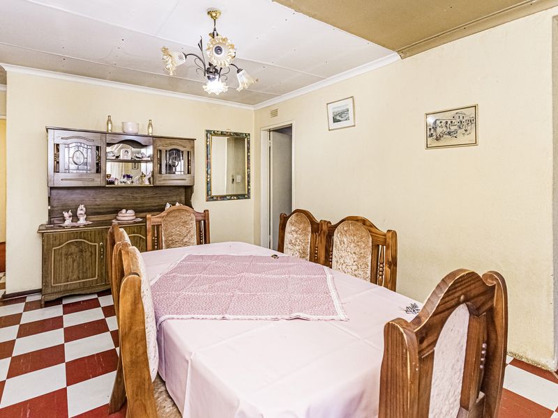 A traditional dining room featuring checkered floor tiles and a central light fixture, offering a dated aesthetic ready for modern updates.