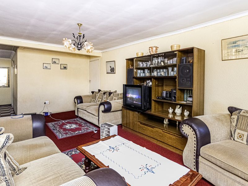 A spacious living room featuring textured walls and carpeted flooring, offering a traditional layout with potential for modern updates.