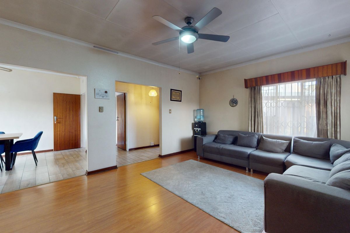Spacious living room featuring laminate flooring, a ceiling fan, and an open-plan layout connecting to an adjacent dining area.