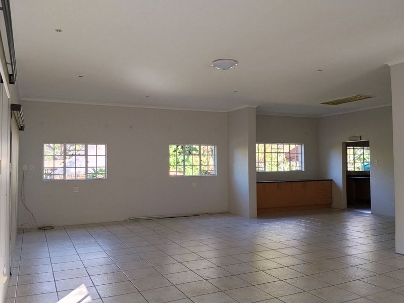 Spacious open-plan living area featuring tiled flooring, recessed lighting, and a functional kitchen nook with built-in cabinetry.
