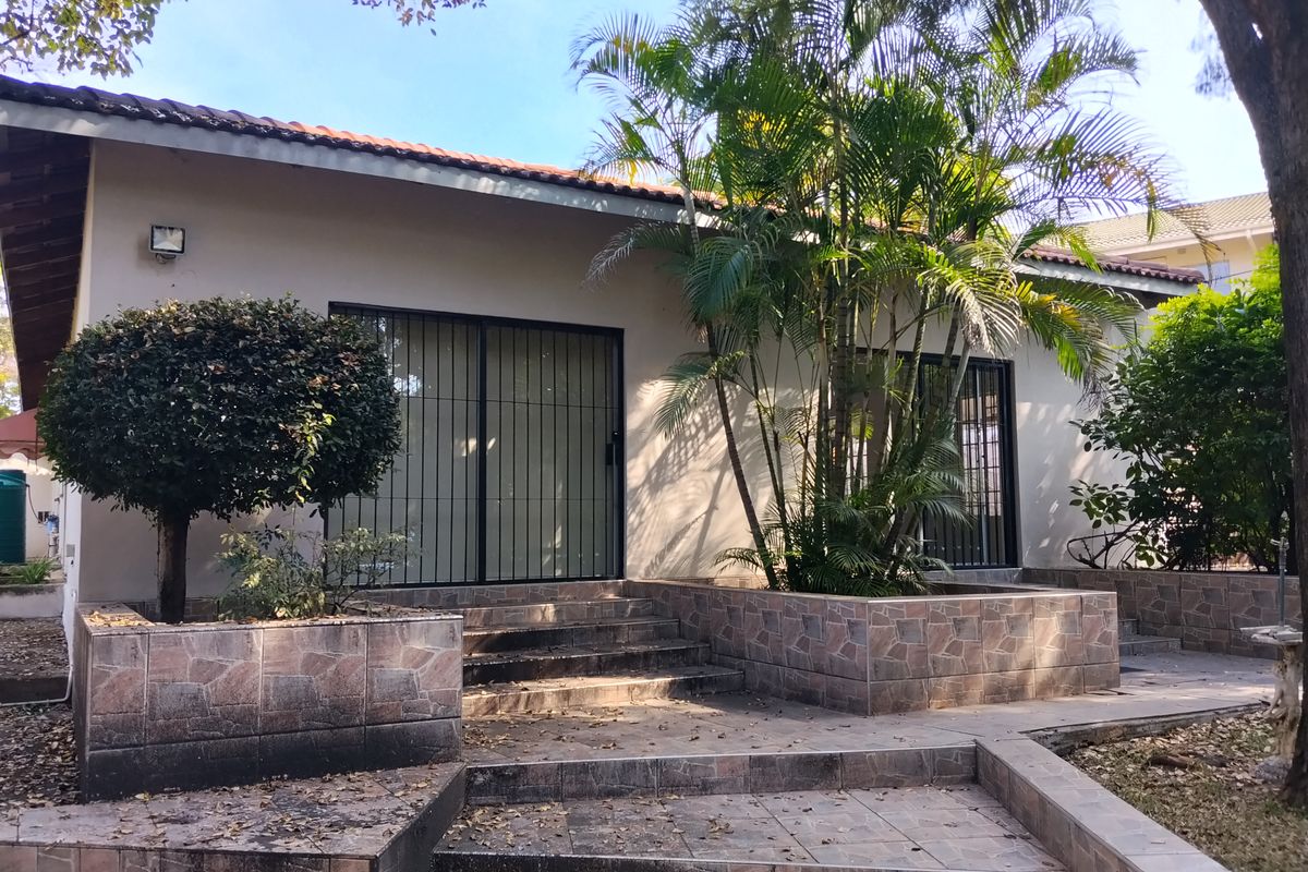 Rear exterior view featuring a tiled patio area, stone-clad planter boxes, and sliding glass doors with security gates.