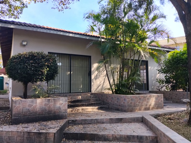 Rear exterior view featuring a tiled patio area, stone-clad planter boxes, and sliding glass doors with security gates.