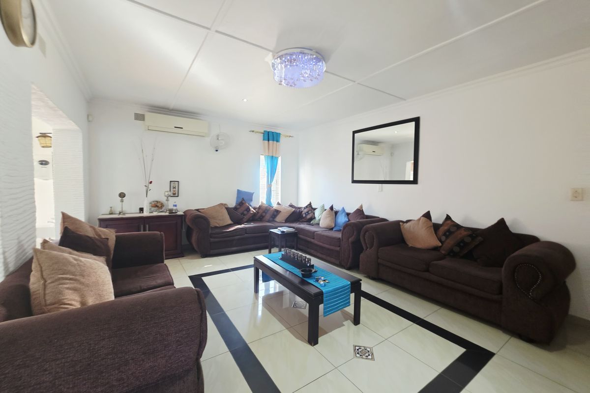 Spacious living room featuring tiled flooring with a decorative border, split-system air conditioning, and a central ceiling light fixture.