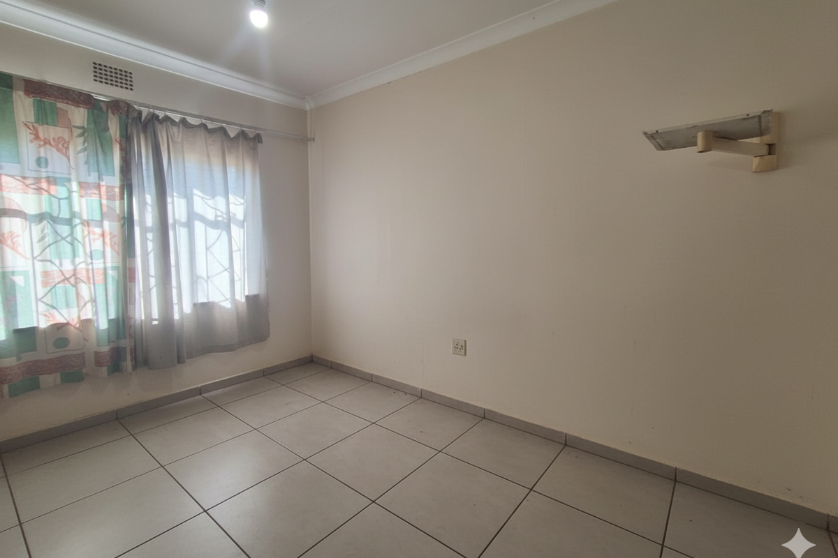 A vacant bedroom featuring neutral tiled flooring, coving, and a wall-mounted shelf, offering a blank canvas for personalization.