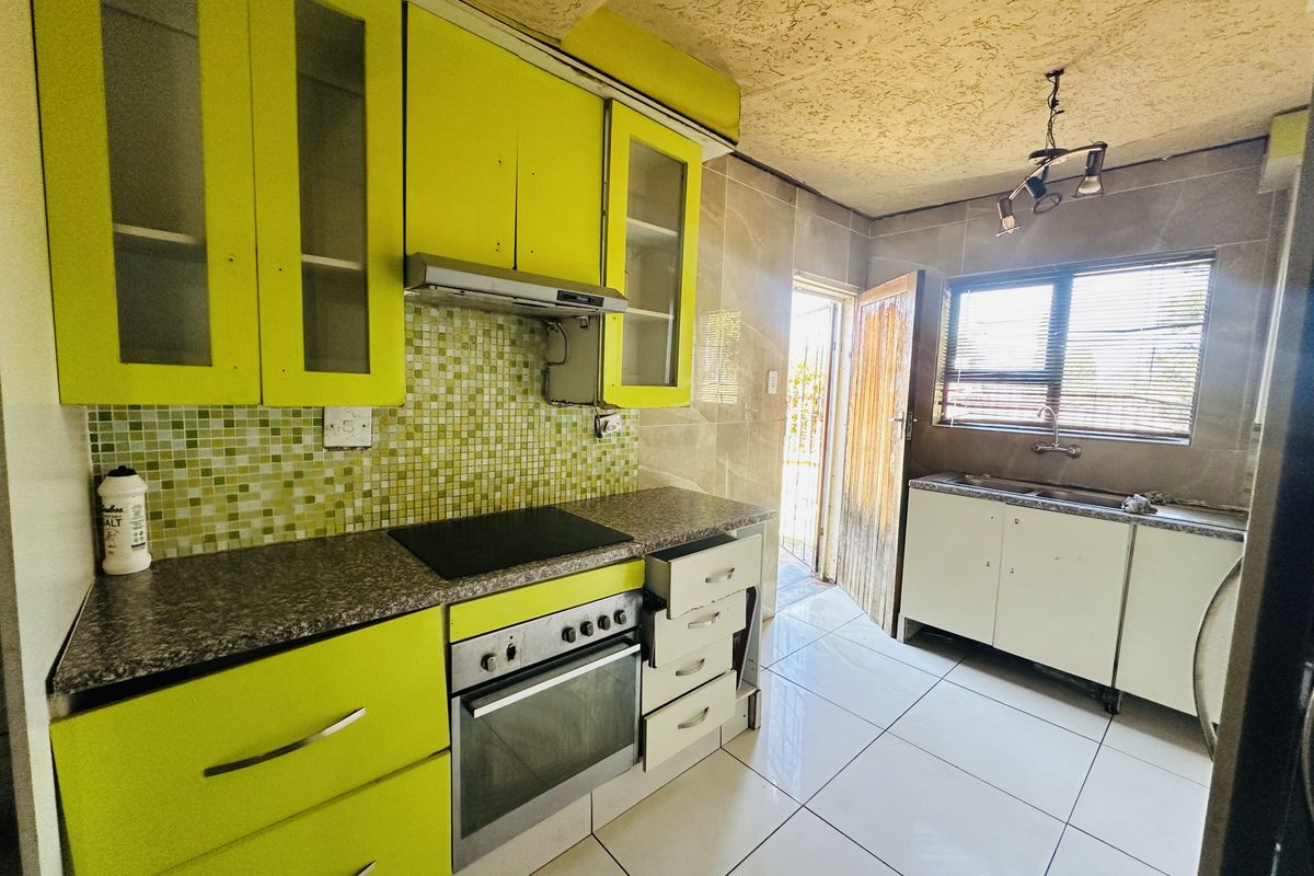 Kitchen featuring lime green cabinetry, mosaic backsplash, built-in oven, and tiled flooring, with direct access to the exterior.