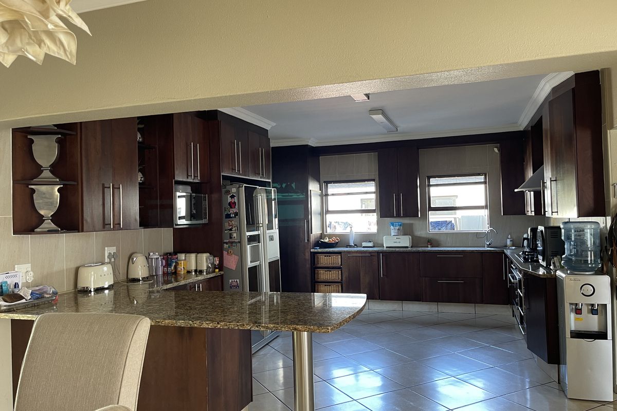 Spacious kitchen featuring dark wood cabinetry, granite countertops, a breakfast bar, and tiled flooring, offering a functional layout with ample storage space.