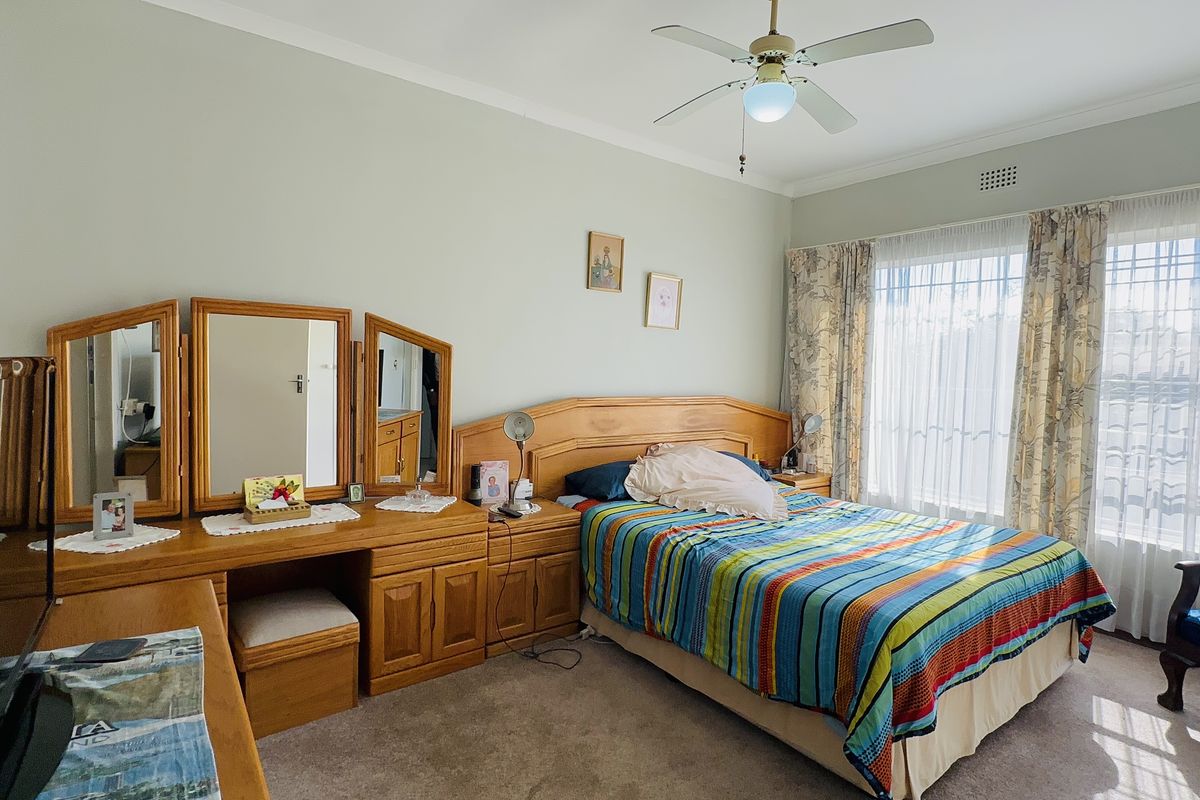 A well-lit bedroom featuring neutral wall tones, carpeted flooring, a ceiling fan, and built-in cabinetry providing ample storage space.