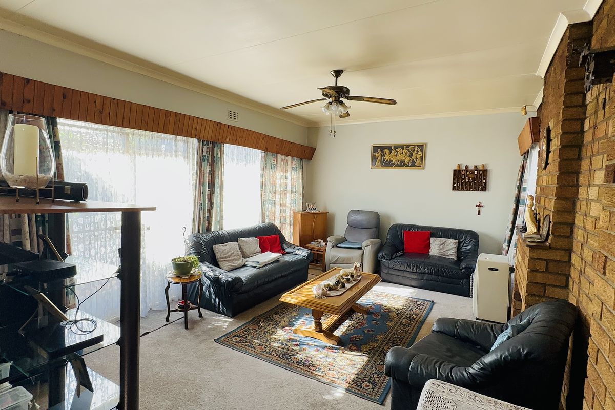 A spacious living room featuring a prominent brick fireplace, ceiling fan, and large sliding glass doors that provide ample natural light.
