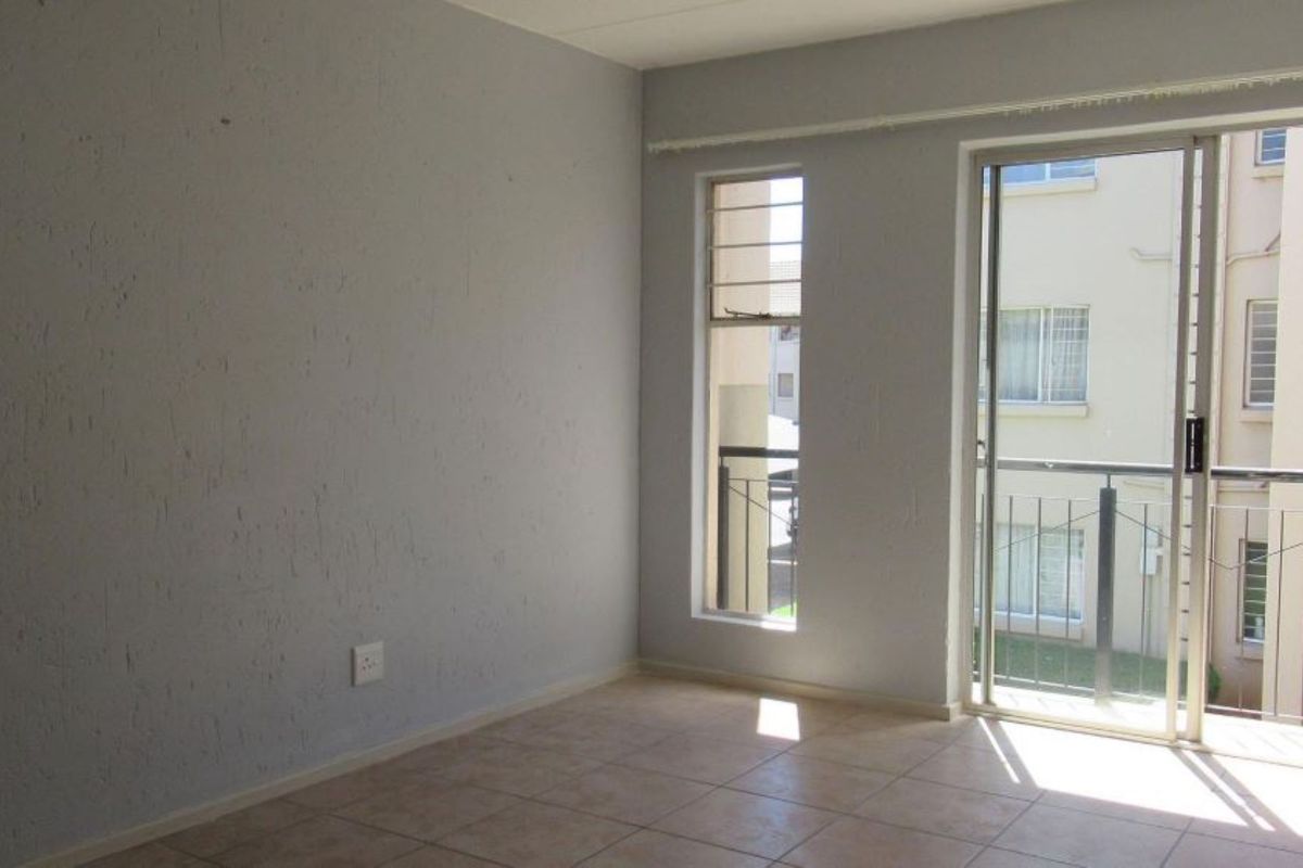 An empty bedroom featuring tiled flooring, a sliding glass door with security bars, and neutral wall finishes.
