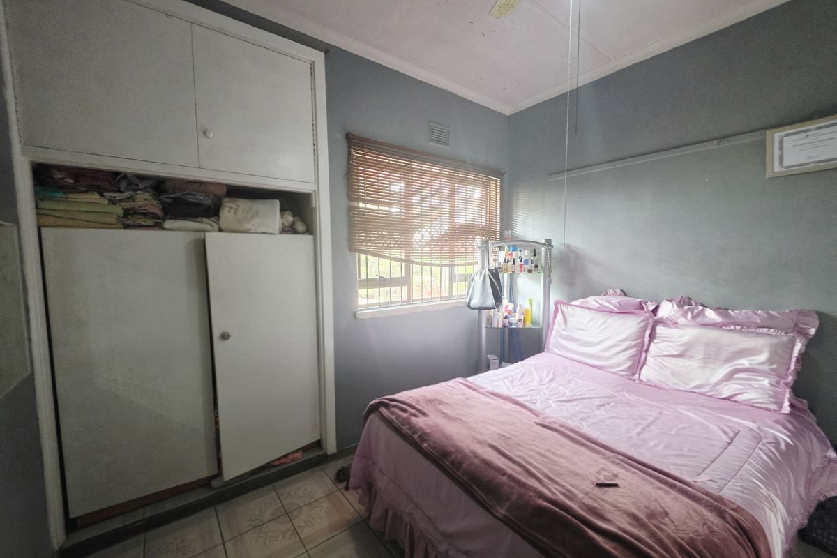 A bedroom featuring built-in cupboards, tiled flooring, and a ceiling fan, requiring cosmetic updates to improve its overall condition.