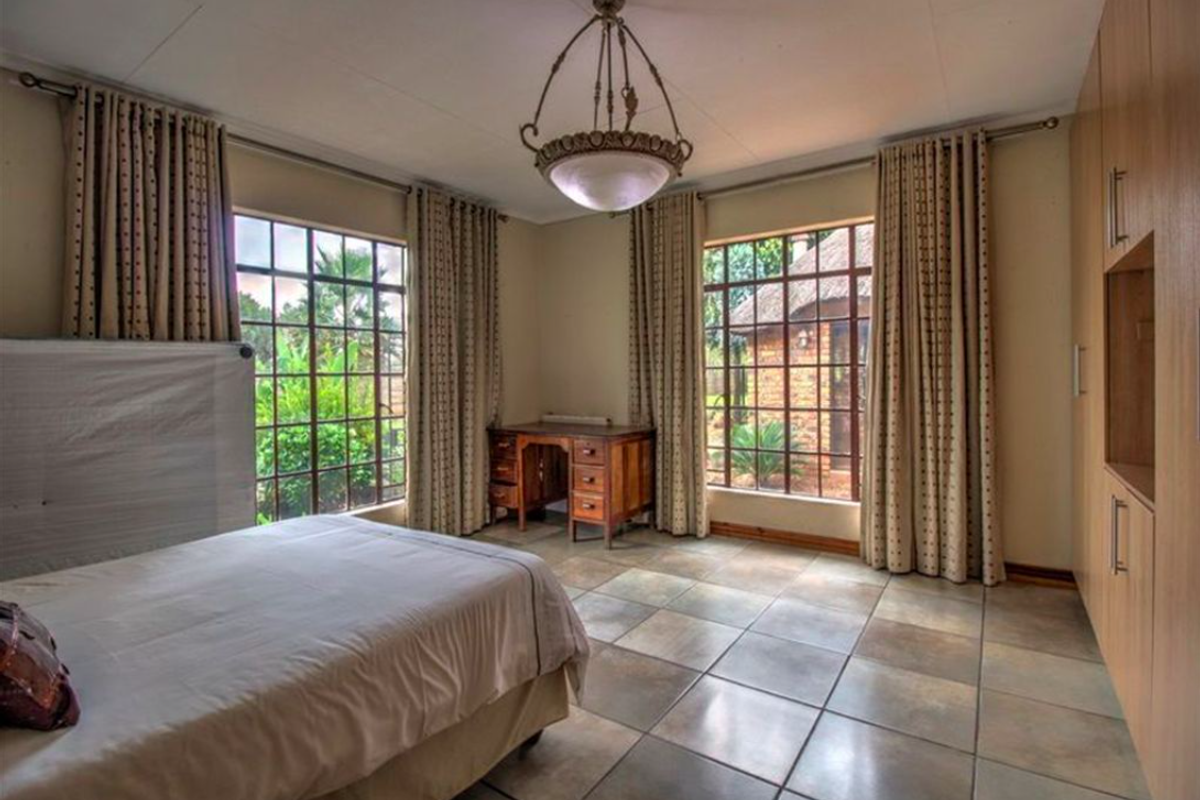 Spacious bedroom featuring large windows, tiled flooring, and extensive built-in cupboard storage, offering a bright and functional living space.