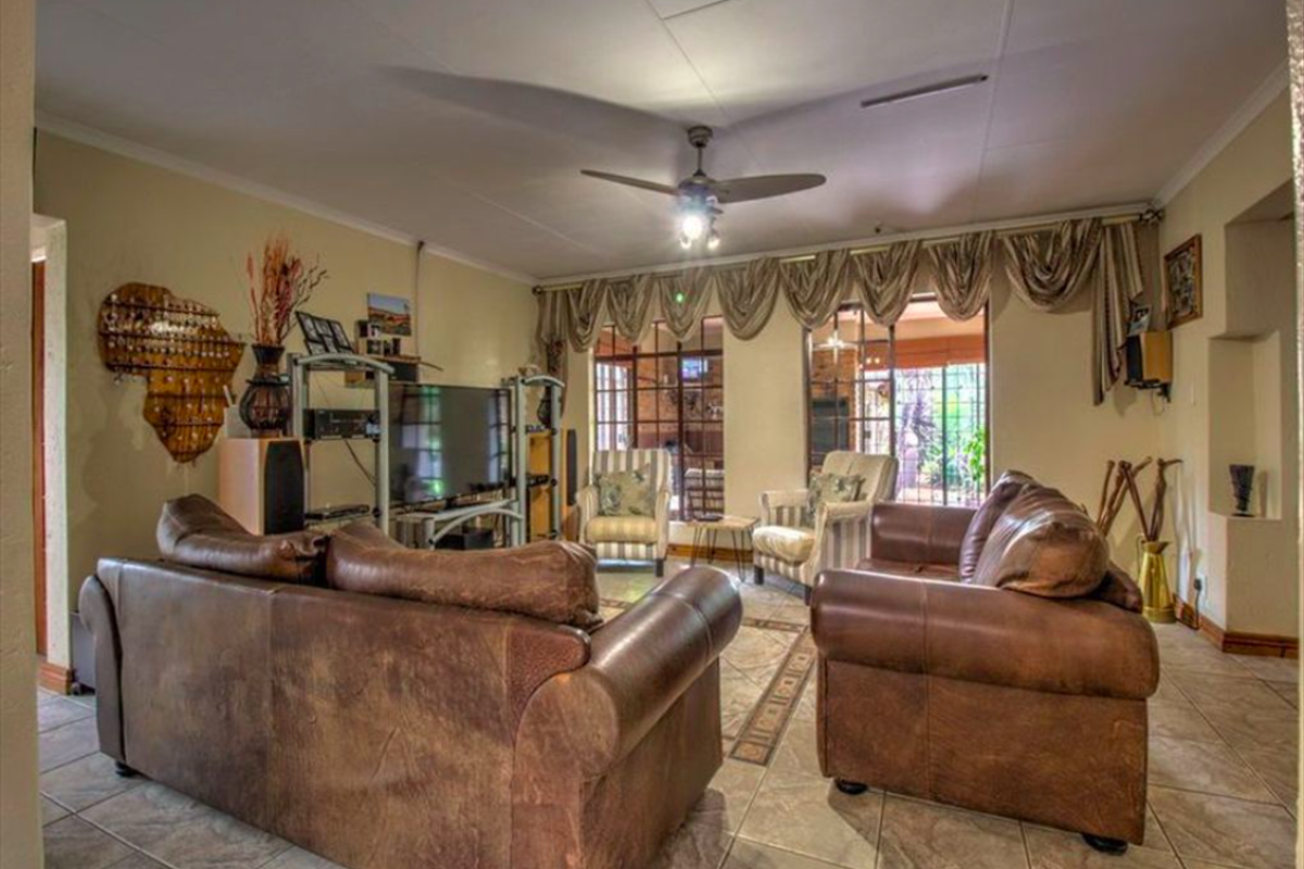 Spacious living room featuring tiled flooring, a ceiling fan, and large sliding glass doors providing access to the outdoor area.