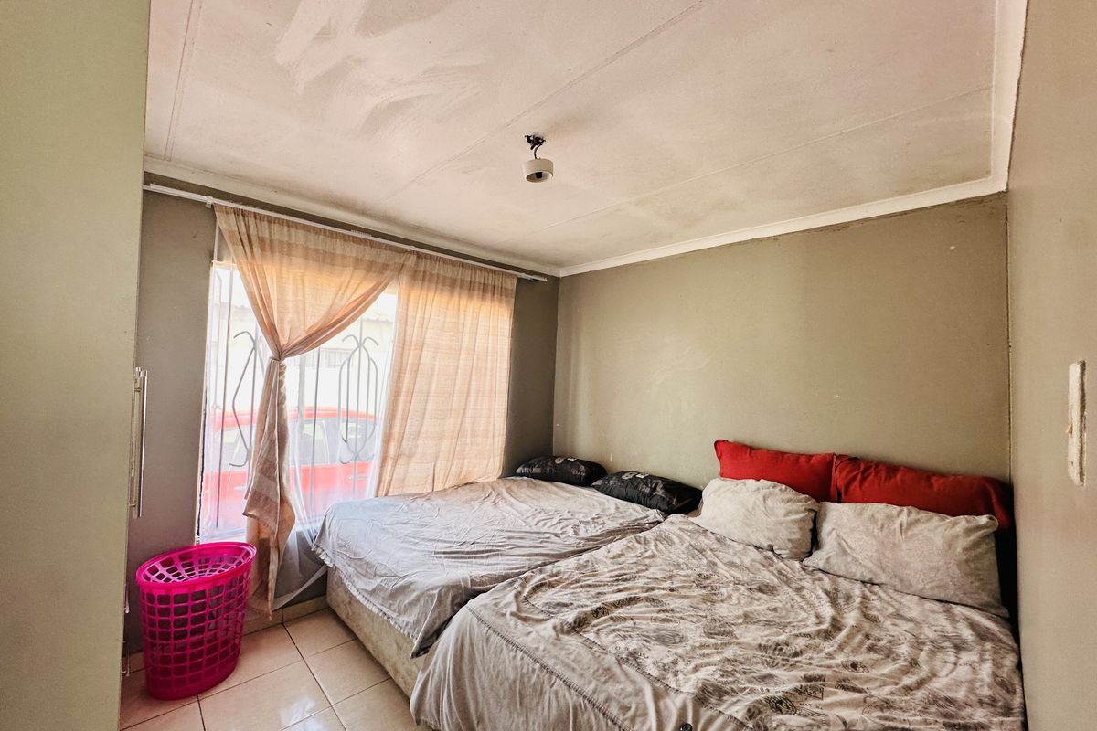 A bedroom featuring tiled flooring and security bars on the window, currently requiring cosmetic updates to the ceiling and wall finishes.
