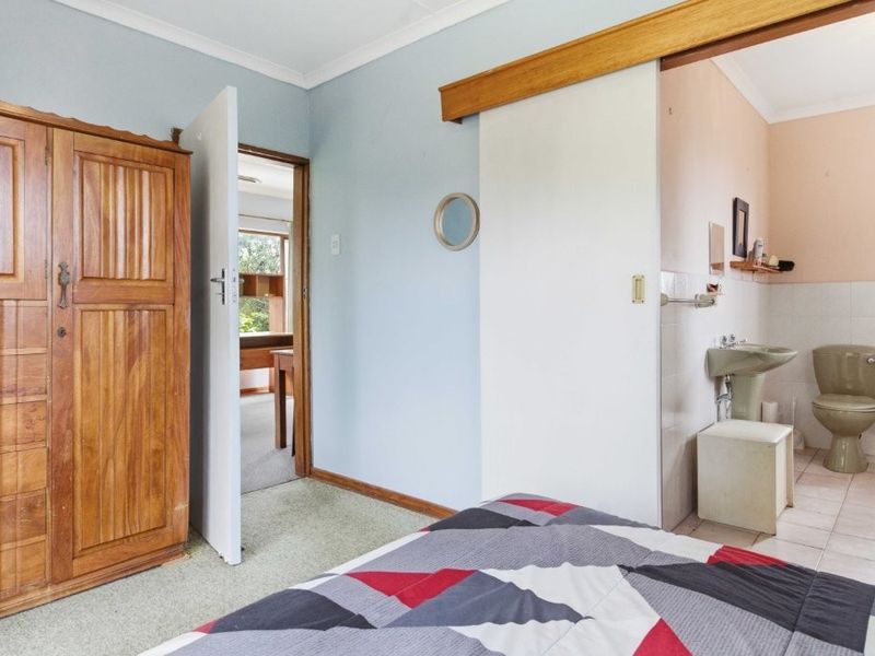 Bedroom featuring an en-suite bathroom with a pedestal basin and toilet, accessible via a sliding door.