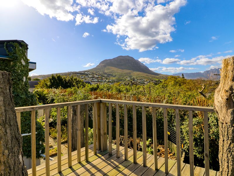 Elevated wooden deck offering expansive mountain and landscape views, featuring a rustic timber balustrade and integrated chimney structure.